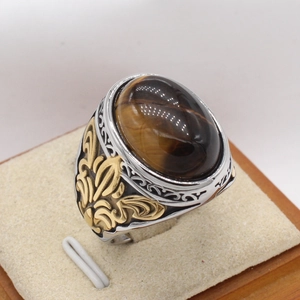 Detailansicht eines Vintage-Herrenrings mit Tigerauge und goldenen floralen Schnitzereien