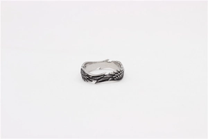 Macro detail of retro stainless steel wing ring with vintage oxidized finish and fine texture