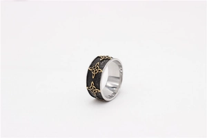 Detailed close-up of retro titanium steel ring with black rock texture and gold Celtic knots