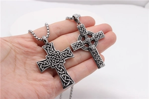 Gros plan de deux pendentifs croix celtique vintage aux motifs de nœuds gravés