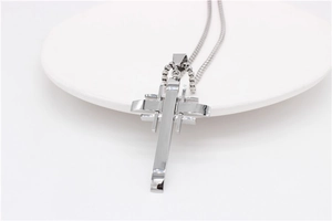 Macro shot of silver cross pendant with layered geometric lines on round white display