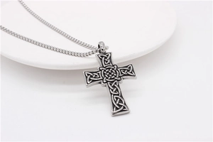 Détail du pendentif croix celtique argentée avec des motifs de nœuds gaufrés complexes