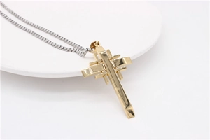 Detailed close-up of a golden geometric cross pendant with a silver box chain