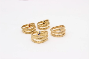 Detalle de cuatro anillos de serpiente dorados con gemas de varios colores