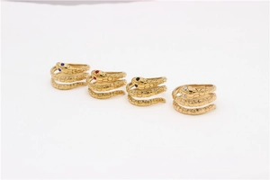 Vista de cuatro anillos de serpiente dorados con ojos de strass sobre tela blanca