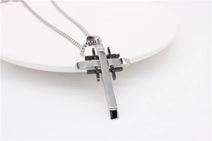 Macro shot of silver and black layered cross pendant with geometric metal grid design