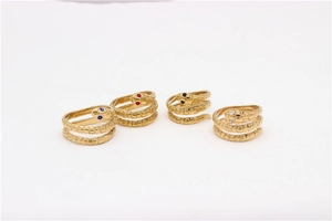 Detalle macro de cuatro anillos de serpiente dorados con ojos de gemas de colores y escamas