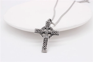 Gros plan détaillé du pendentif croix celtique vintage avec des nœuds sur céramique blanche