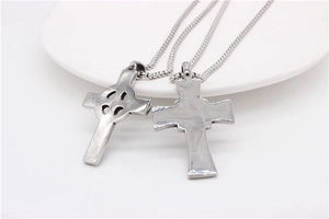 Détail de pendentifs croix celtique viking avec chaînes à billes sur plateau blanc