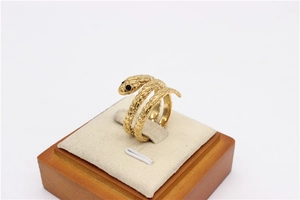 Detalle de anillo de serpiente dorado con texturas de escamas y pequeños ojos de piedra negra