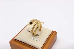 Detalle de anillo de serpiente dorado con escamas talladas y ojos de piedras negras