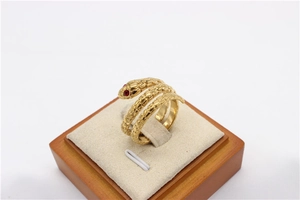 Detalle de anillo de serpiente dorado vintage con ojos rojos en soporte de terciopelo