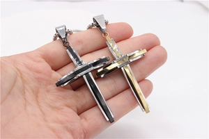 Gros plan sur les pendentifs croix à trois couches en acier titane avec détails noirs et ors