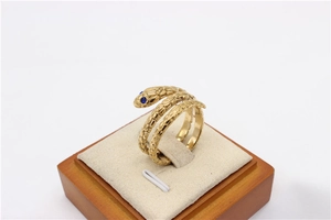 Detalle de anillo de serpiente dorado con ojos de gemas azules y textura de escamas