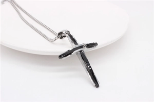 Détail d'un pendentif en forme de croix en acier inoxydable argenté et inserts noirs