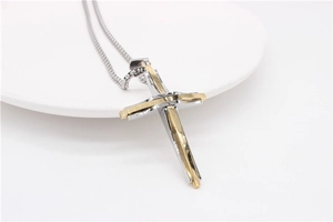 Gros plan sur un pendentif en forme de croix bicolore en acier inoxydable or et argent