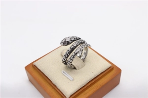 Vista de detalle de anillo de serpiente plateado con escamas y cristal incrustado