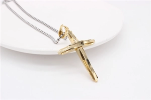 Vue macro d'un pendentif croix géométrique doré sur une chaîne en acier argenté