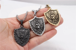 Vue détaillée du pendentif bouclier rétro avec relief d'archange en or, argent et noir