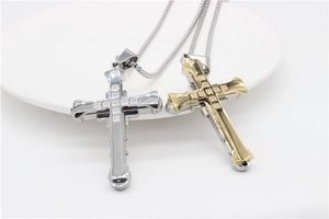 Détail de pendentifs croix or et argent sertis de zircons sur un plateau blanc