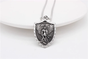 Détail du pendentif bouclier argenté avec relief d'ange sur une chaîne serpent fine