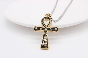 Macro detail of gold Ankh cross pendant with black enamel and Egyptian hieroglyphs