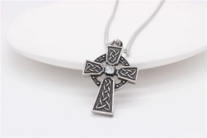Gros plan d'un collier croix celtique argenté avec cristal central et chaîne serpent