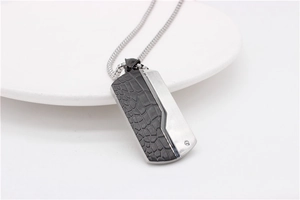 Detail of dual-texture dog tag necklace with faux leather inlay and brushed steel finish