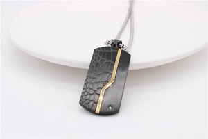 Detail of a rectangular black and gold pendant with crocodile pattern and zircon