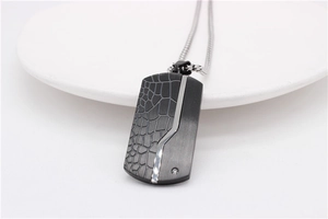 Detailed close-up of men's dog tag pendant with black crocodile texture and silver finish