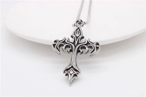 Macro detail of Gothic cross pendant with intricate tribal carvings and a snake chain