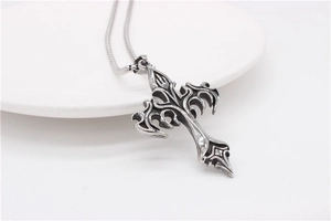 Macro detail of gothic cross pendant with intricate filigree and vintage silver finish