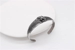 Detailed close-up of a vintage lion head engraving on a silver steel cuff bracelet