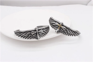 Detail of vintage eagle wings and gothic cross engraving on stainless steel cuff bracelets