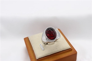 Détail d'une pierre précieuse rouge ovale sertie dans une bague large en titane