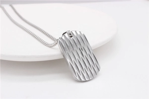 Nahaufnahme des Titanstahl-Dog-Tag-Anhängers mit strukturierter Wellengravur