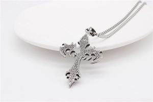Detail of gothic silver cross pendant with vintage distressed texture and punk dark style