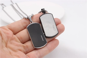 Detailed view of silver and black military tag pendants with diamond-set edges and mesh texture