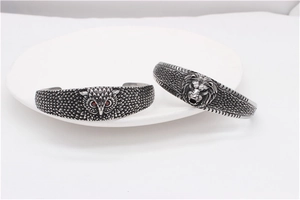 Detailed retro lion head and owl steel cuff bracelets with intricate textures and red eyes