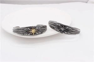 Detailed close-up of retro eagle feather engravings and star patterns on steel bracelets