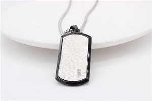 Macro detail of rectangle military dog tag pendant with hammered texture and black border