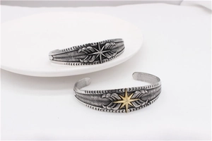 Detail view of vintage stainless steel cuff bracelet with feather textures and star motif