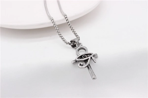 Detailed close-up of vintage steel Ankh cross pendant with Eye of Horus on white fabric