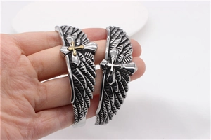 Close-up of vintage steel eagle wing bracelets with gold and silver crosses on wrist
