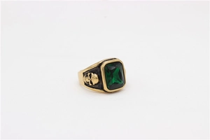 Detail of vintage gold-finished ring with emerald-green stone and skull relief