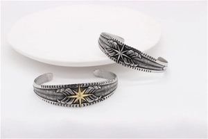 Detail of vintage feather wing cuff bracelets with star patterns in silver and gold colors