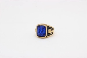 Detailed macro view of gold-tone skull ring with large blue rectangular gemstone