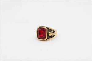 Detail of gothic ring featuring a red gemstone inlay and carved skull side patterns