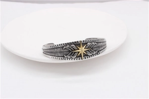 Detailed view of vintage steel cuff bracelet with golden star and feather texture