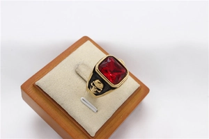 Detail view of gold skull ring with a large rectangular red gemstone in punk style